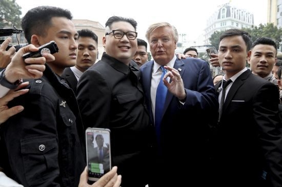 하워드 X는 지난해 6월 싱가포르에서 개최된 1차 북미회담 때에도 김 위원장 스타일을 따라 하고 거리에 나타나<br>
화제가 된 바 있다. 도널드 트럼프 미국 대통령으로 분장한 러셀 화이트(오른쪽 두 번째)와 김정은 북한 국무위원장<br>
으로 분장한 하워드 엑스가 베트남 하노이 오페라 하우스 앞에서 정상회담의 분위기를 띄우며 포즈를 취하고 있다.<br>
뉴시스