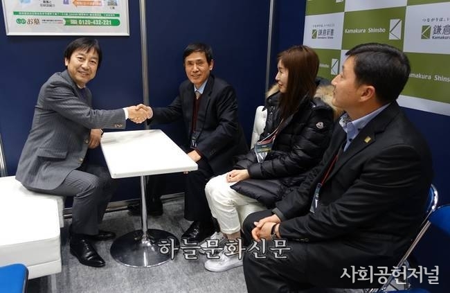 카마쿠라신서 시미즈 사장을 찾아 중권시장 상장을 축하하는장면 (2015년 12월 도쿄장례박람회 현장)