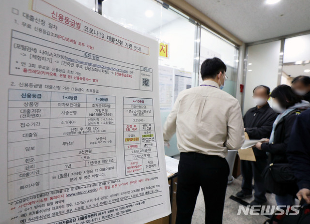 정부가 4월 1일부터 소상공인진흥기금을 통한 1000만원 대출은 출생연도에 따라 '홀짝제'로 운영한다고 밝힌 가운데 30일 오전 서울 종로구 소상공인시장진흥공단 서울중부센터에서 한 관계자가 한 소상공인에게 신용등급별 코로나19 대출신청 기관 안내문을 들고 설명하고 있다. 사진 출처 : 뉴시스