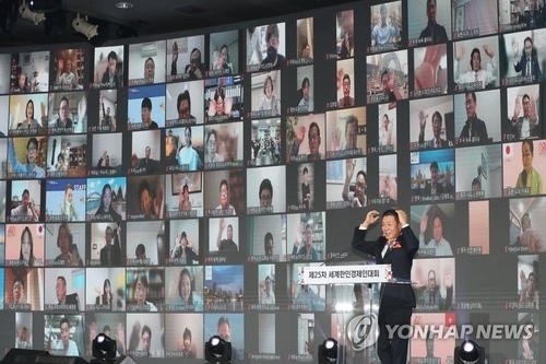 <strong>온라인으로 행사에 참여하는 회원들과 인사 나누는 하용화 회장</strong><br>
하용화 세계한인무역협회장이 12일 서울시 광진구 워커힐 호텔에서 열린 세계한인경제인대회에서 개회사를 하며 온라인 참여자들에게 인사하고 있다