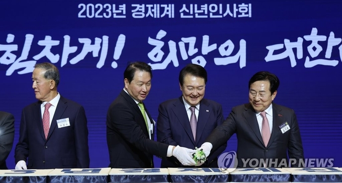 경제인 만난 윤석열 대통령/ 윤석열 대통령이 2일 오후 서울 강남구 코엑스에서 열린 2023 경제계 신년인사회에서 경제인들과 떡을 자르고 있다. 왼쪽부터 허창수 전국경제인연합회 회장, 최태원 대한상공회의소 회장, 윤 대통령, 김기문 중소기업중앙회 회장. 2023.1.2 