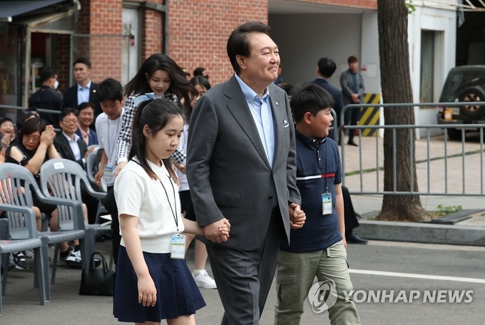 어린이들과 손잡고 용산어린이정원 입장하는 윤 대통령 부부 / 윤석열 대통령과 부인 김건희 여사가 4일 서울 용산 대통령실의 앞마당에 조성된 용산 어린이정원에 어린이들과 손을 잡고 입장하고 있다. 2023.5.4 